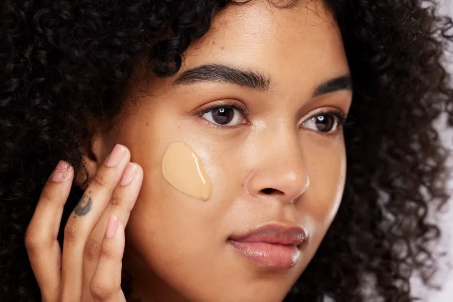 A woman with a glob of foundation on her cheek.